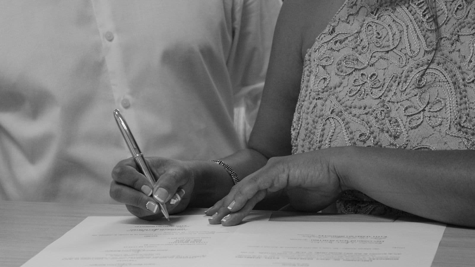 Two people signing settlement paperwork at a table