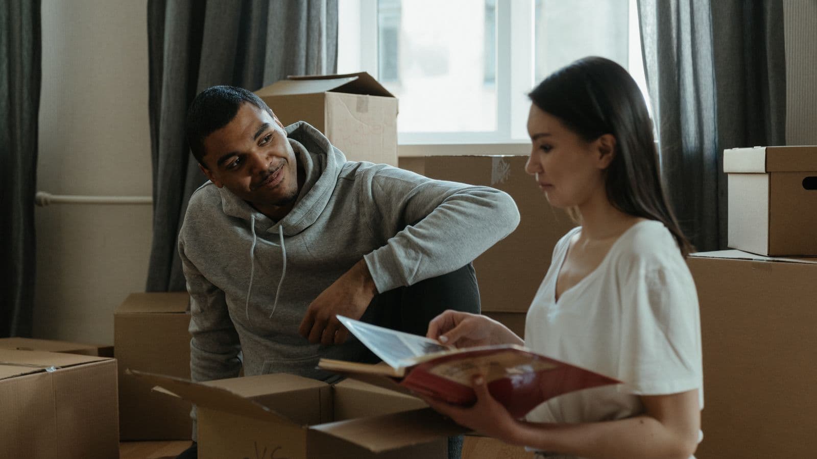 Couple packing belongings and looking through a photo album while downsizing their home