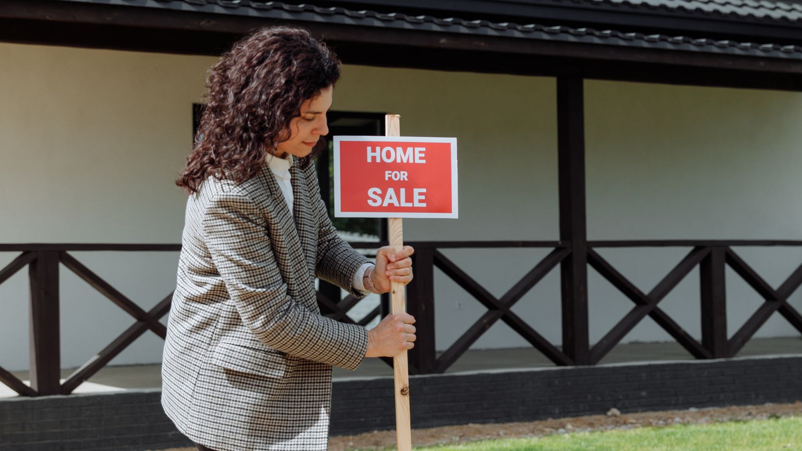 Real estate agent placing a home-for-sale sign on a front lawn